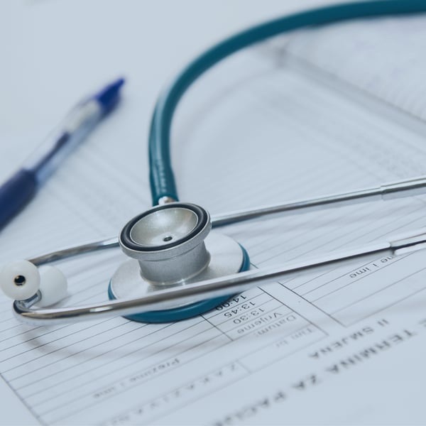 A stethoscope placed on a sheet of paper with a pen, representing the healthcare industry